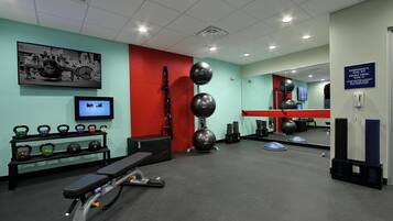 A gym with exercise equipment, a television, and a mirror.