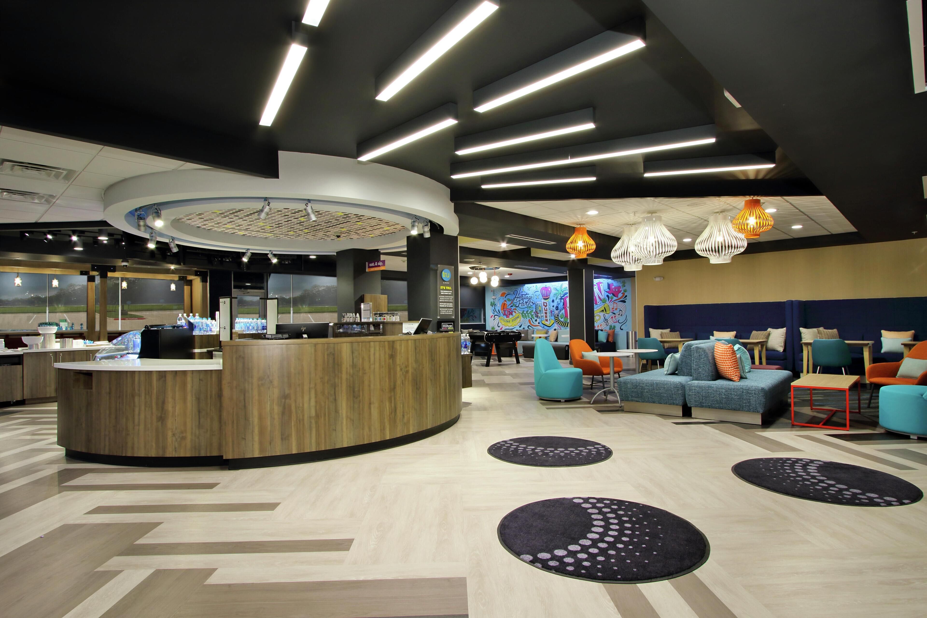 A modern lobby with a reception desk, seating area, and a large digital screen.