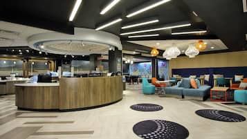 A modern lobby with a reception desk, seating area, and a large digital screen.