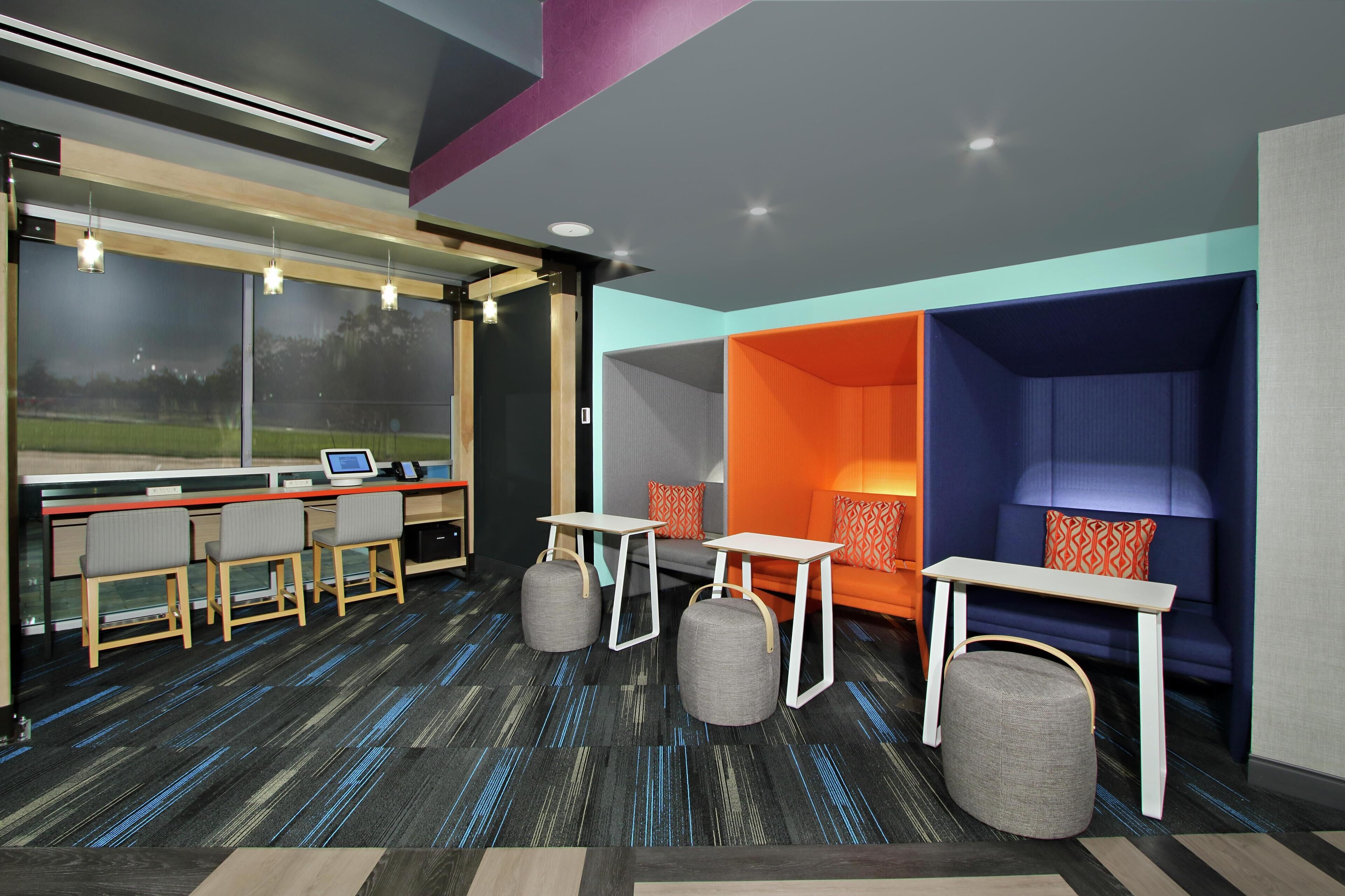 A modern hotel room with a desk, chairs, a sofa, and a small table.