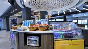 Un quiosco moderno con diversas bebidas, un microondas y una máquina expendedora.