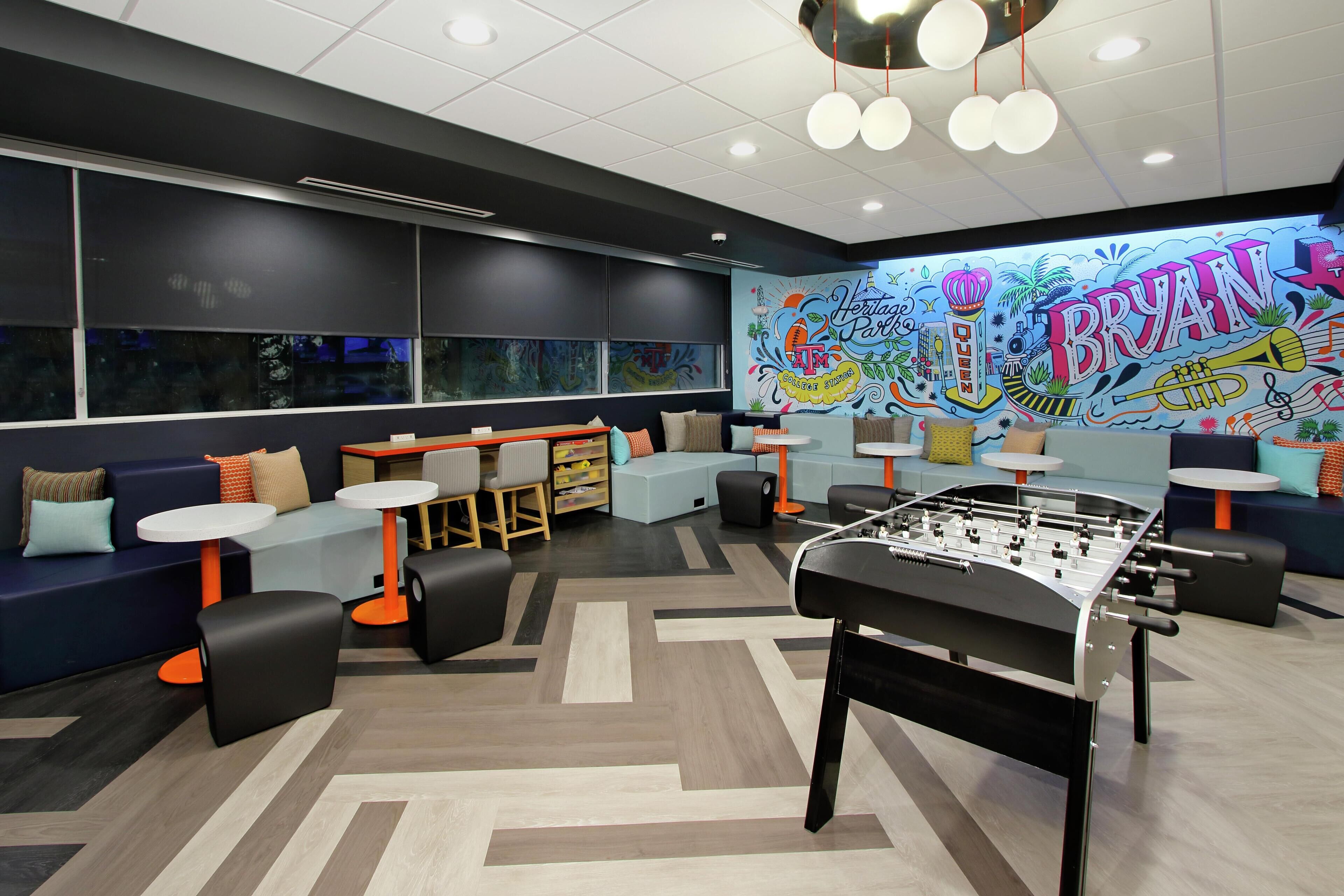 Un espacio lounge moderno con asientos, mesas y una mesa de futbolín.