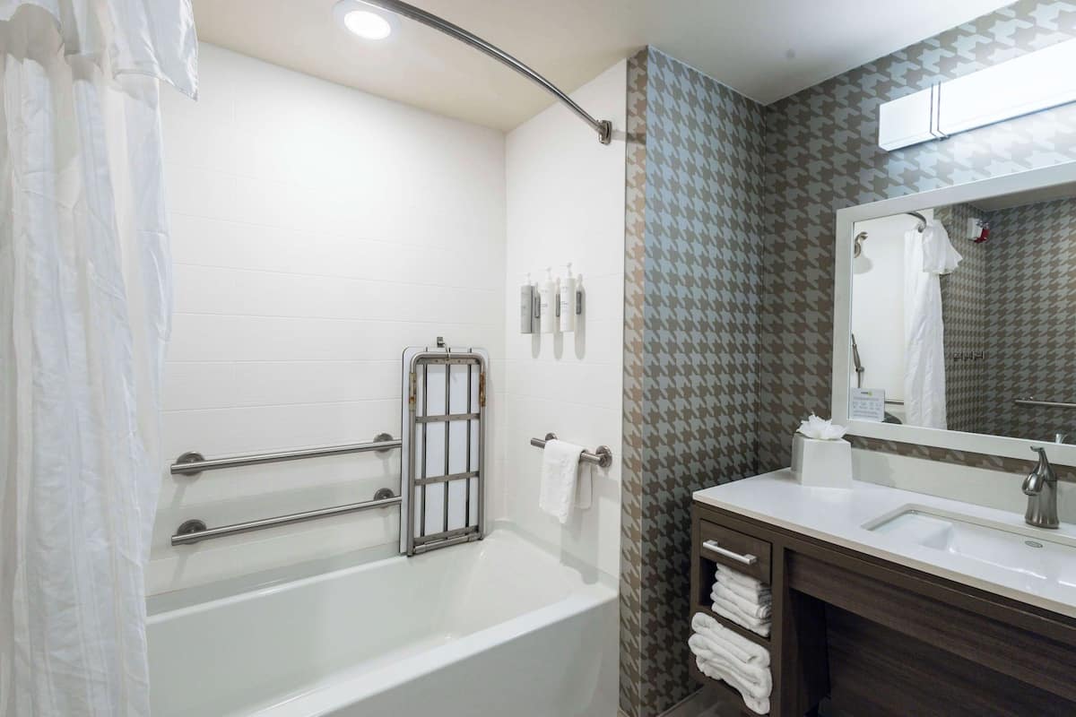 Ein modernes Badezimmer mit Badewanne, Waschtisch mit Spiegel und Duschbereich.