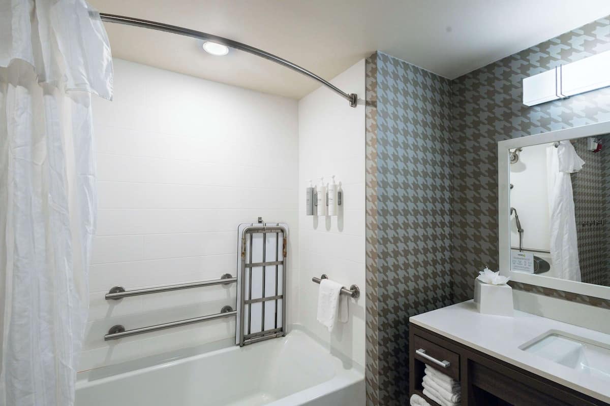 Ein modernes Badezimmer mit Badewanne, Dusche, Waschtisch inklusive Spiegel und Handtuchhalter.