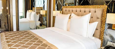 A hotel room with a large bed, a mirror, a bedside table with a lamp, and a telephone.