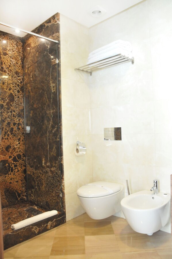 A bathroom with a glass-enclosed shower, a toilet, and a bidet.