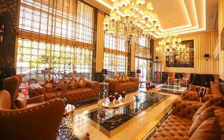 A luxurious lobby with plush seating, a grand chandelier, and large windows with decorative grills.
