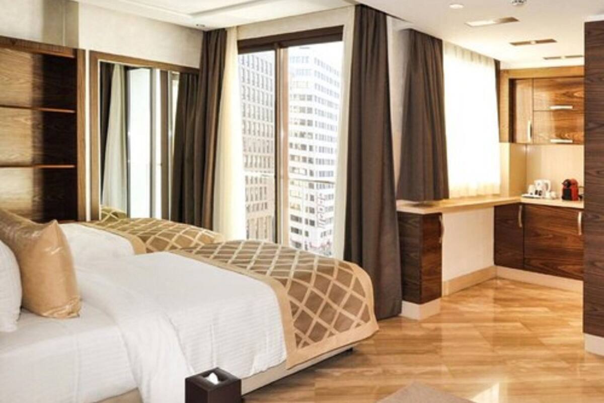 Ein modernes Hotelzimmer mit einem großen Bett, einem Schreibtisch und Blick auf eine Stadtlandschaft.