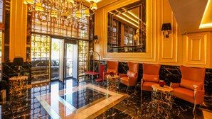 Een luxe lobby met een kroonluchter, een zithoek en een grote spiegel.