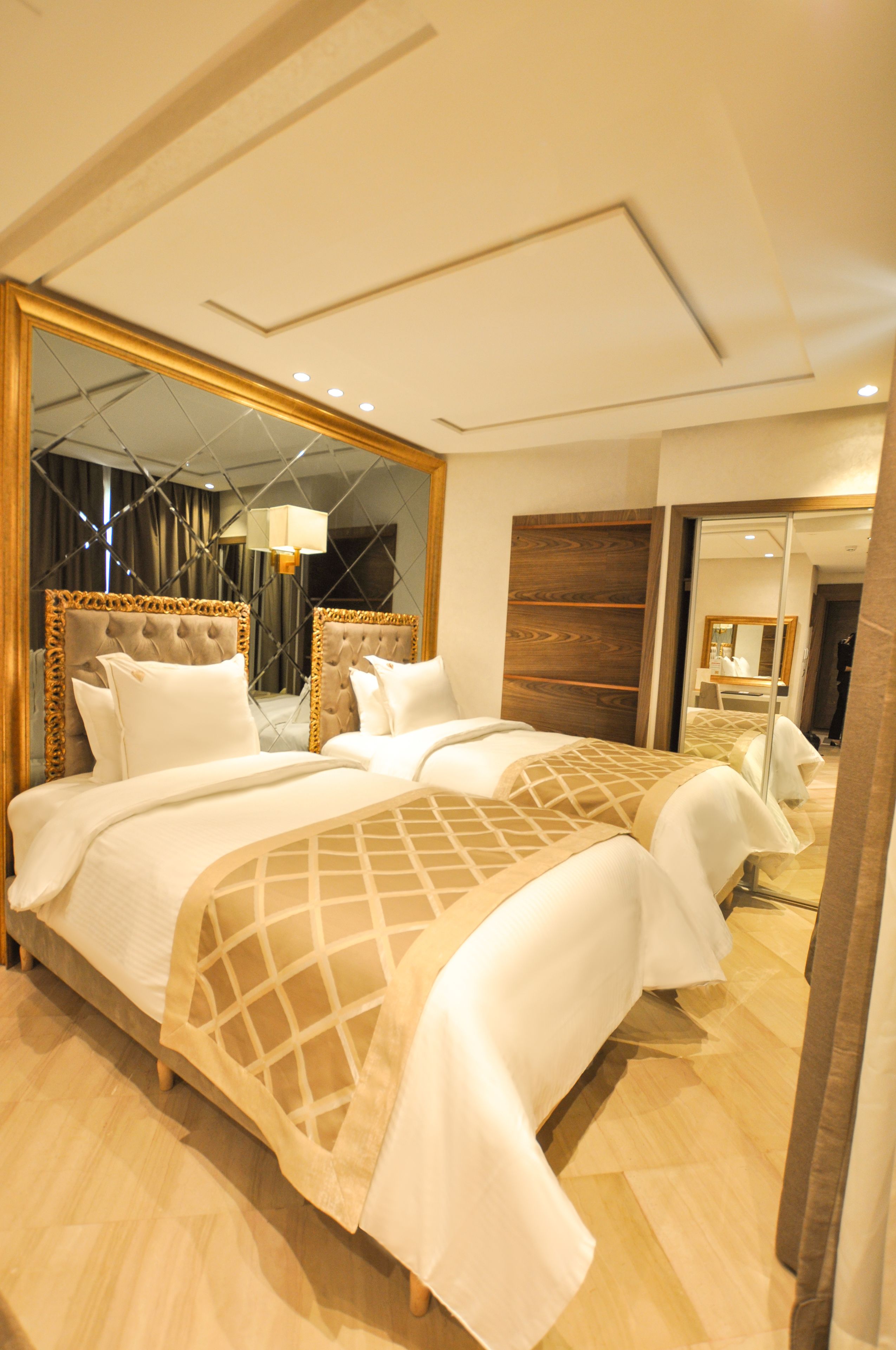 A hotel room with a large bed, a mirror, and a wooden headboard.