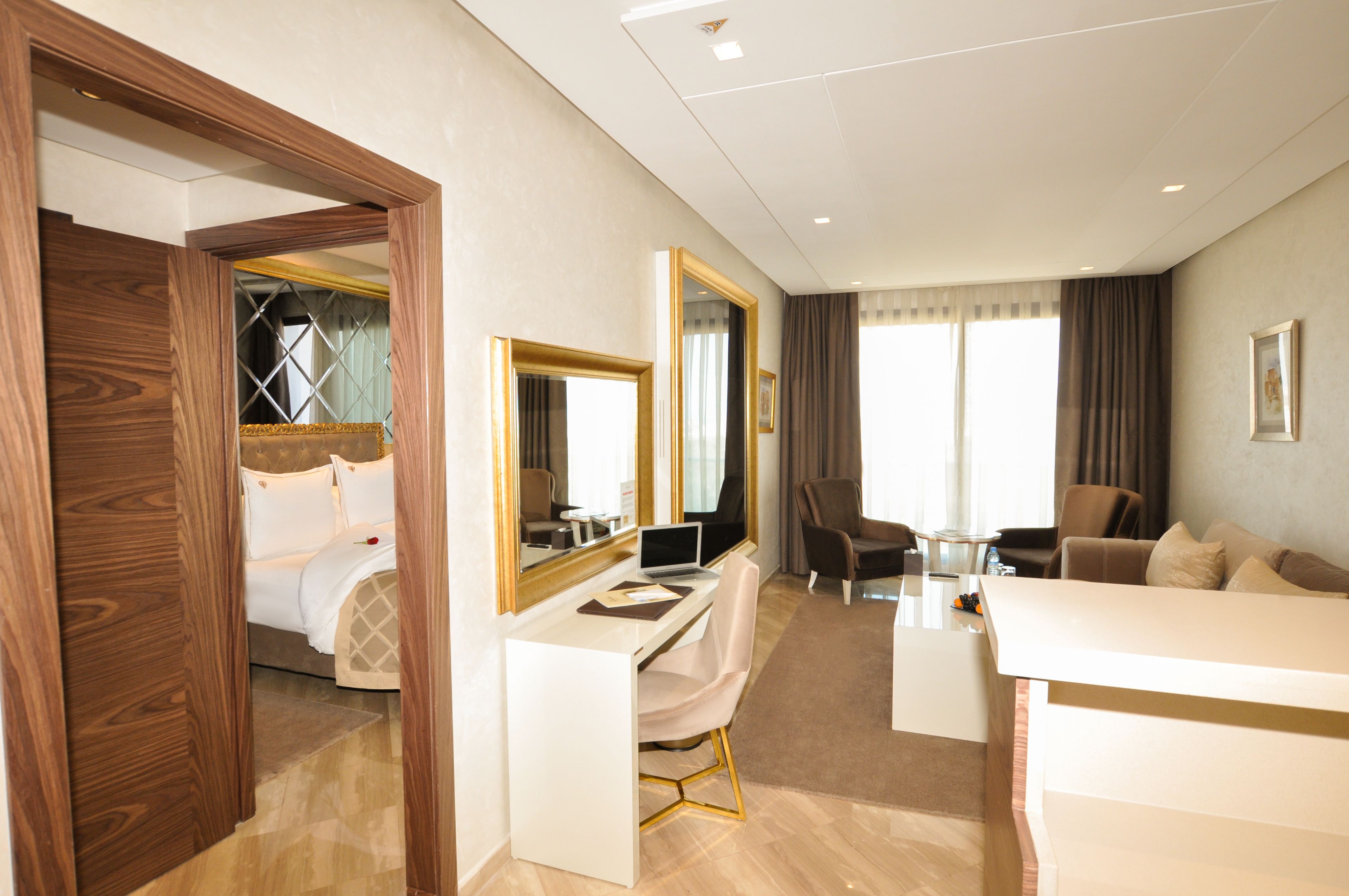 Une chambre d’hôtel avec un lit, un bureau avec un ordinateur portable, une chaise, un canapé et un grand miroir.