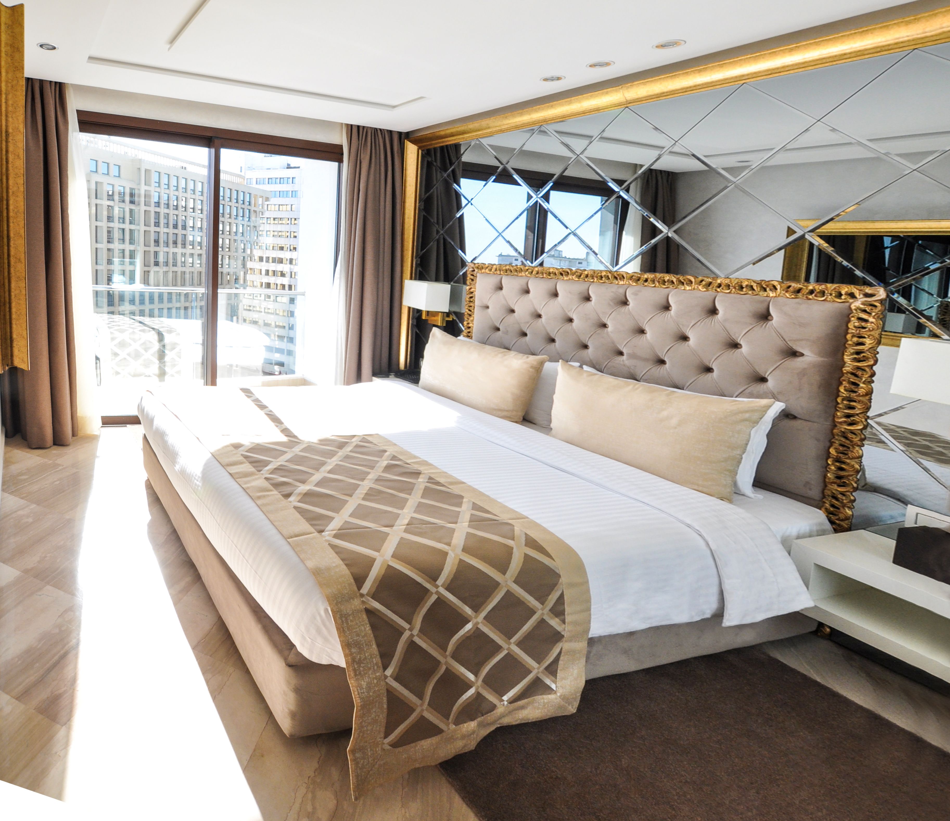 Habitación de hotel moderna con una cama grande, vistas a la ciudad y un balcón.
