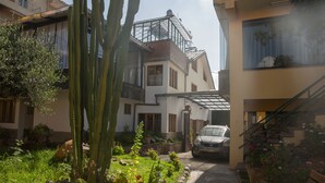 A residential area with a car parked in the driveway, a staircase, and a garden with cacti and plants. - Hospedaje Turismo CAITH (Cusco)