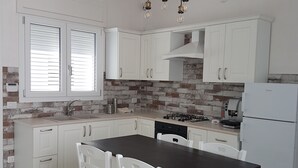 Een moderne keuken met witte kastjes, een donker houten tafel en een witte koelkast.