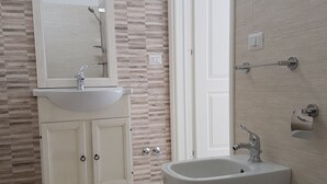 Een badkamer met een wastafel, twee wasbakken, een spiegel en een douche.