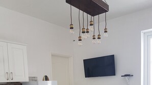 Een keuken met witte kastjes, een witte koelkast, een koffiezetapparaat en een eettafel met witte stoelen.
