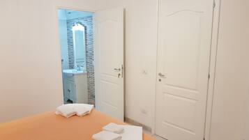 Una camera d'albergo con un letto, un bagno con uno specchio e due porte.