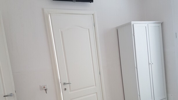 Een slaapkamer met een bed, een kledingkast, een televisie en een deur.