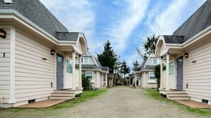 A row of single-story mobile homes with a gravel driveway and a clear sky. - Sea Breeze Cottages (Ocean Shores)