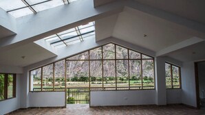 Ein geräumiger Raum mit großen Fenstern, Fliesenboden und schrägverdeckter Decke.