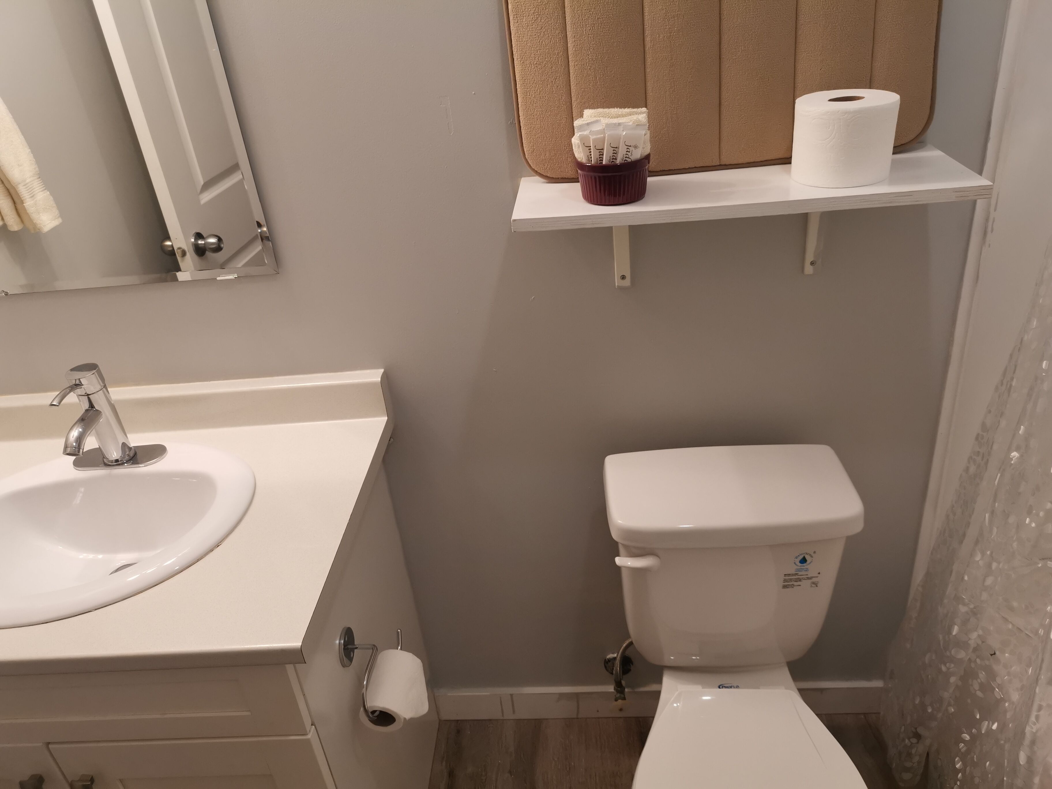A bathroom with a sink, toilet, and a shelf with toiletries.
