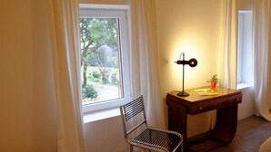 Une pièce avec une chaise, un bureau et une fenêtre avec des rideaux.