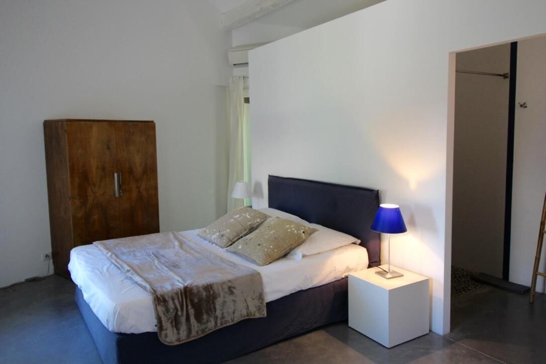 A bedroom with a bed, a nightstand with a lamp, a wardrobe, and a door.