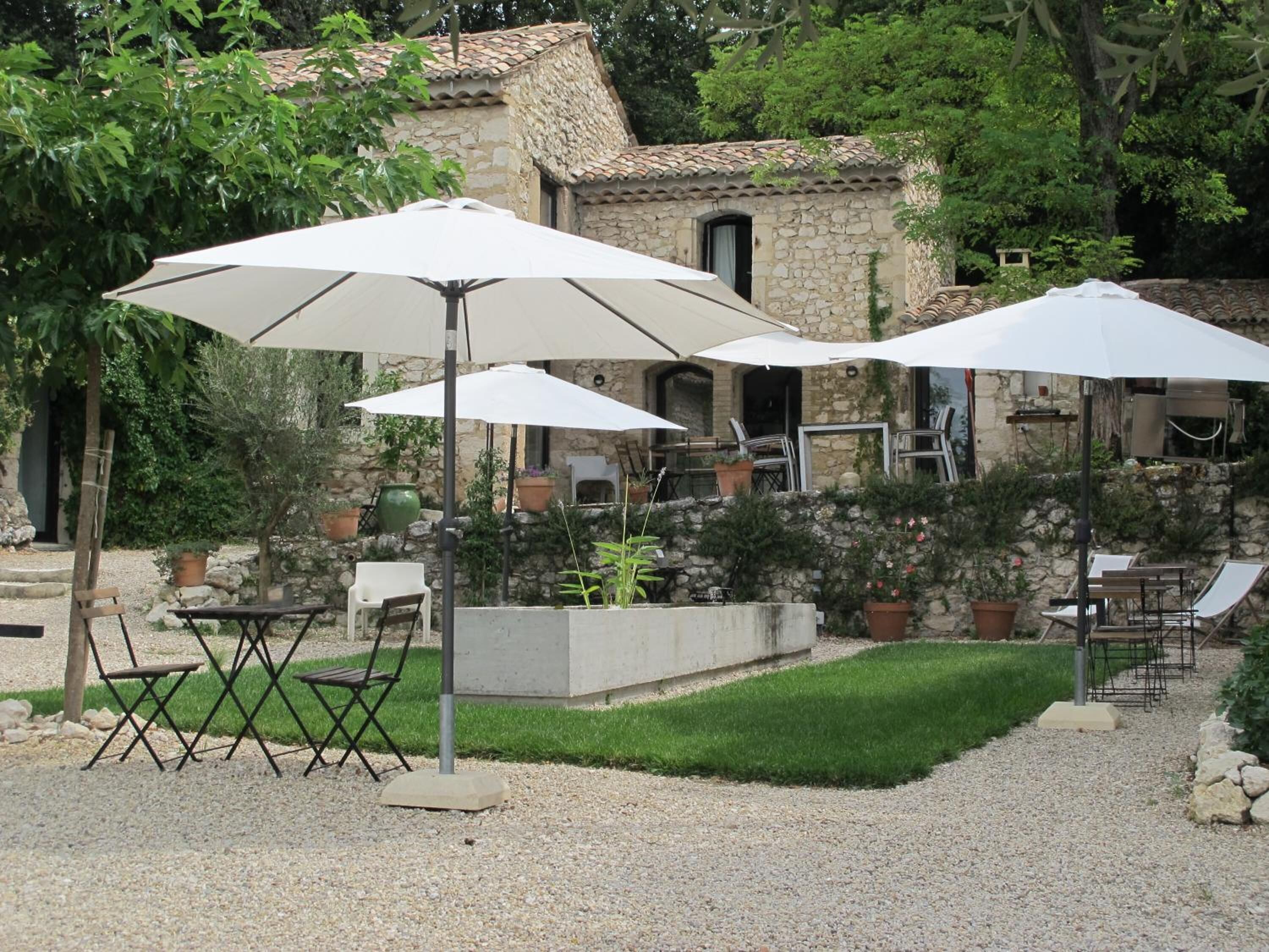 An outdoor patio with white umbrellas, foldable chairs, and a stone building in the background.
