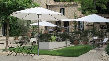 An outdoor patio with white umbrellas, foldable chairs, and a stone building in the background.