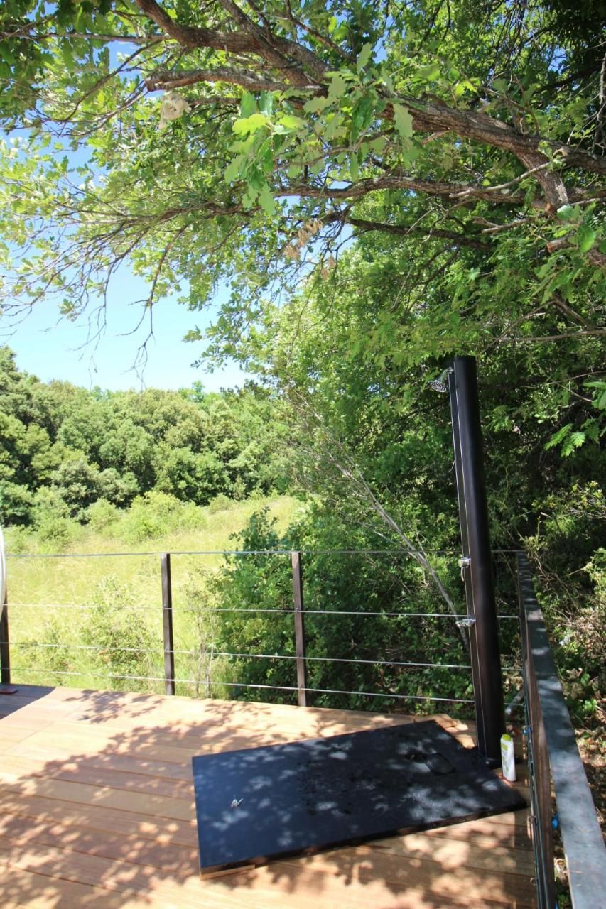 A wooden deck with a metal railing, surrounded by trees and greenery.