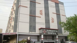 Un edificio con un cartel que dice "LOKHITH TOWER" y un hostal llamado "TH BOYS HOSTEL" debajo.