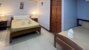 A hotel room with a bed, bedside table, and a small table with a lamp.