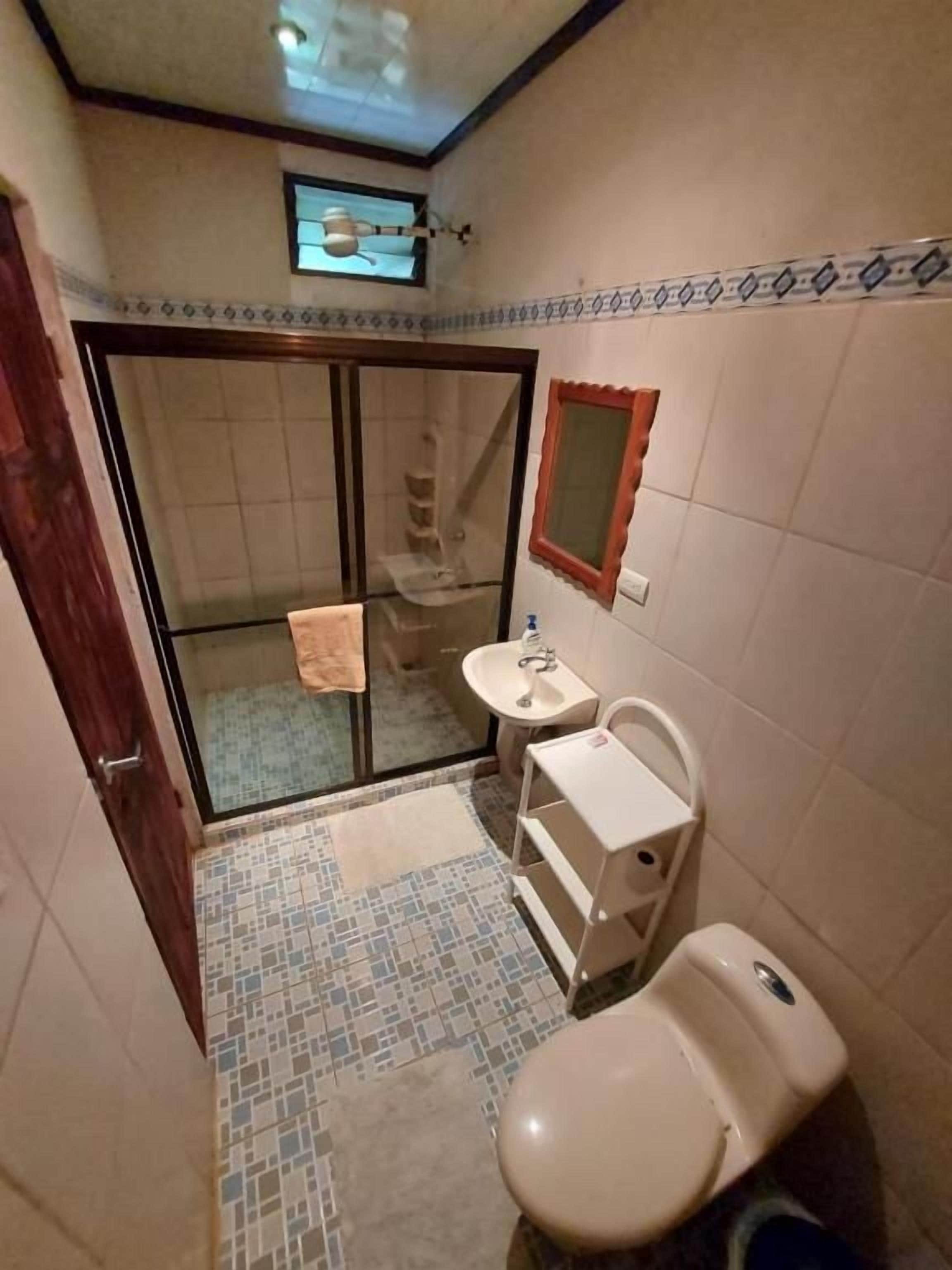Une petite salle de bain comprenant des toilettes, un lavabo et un espace douche.