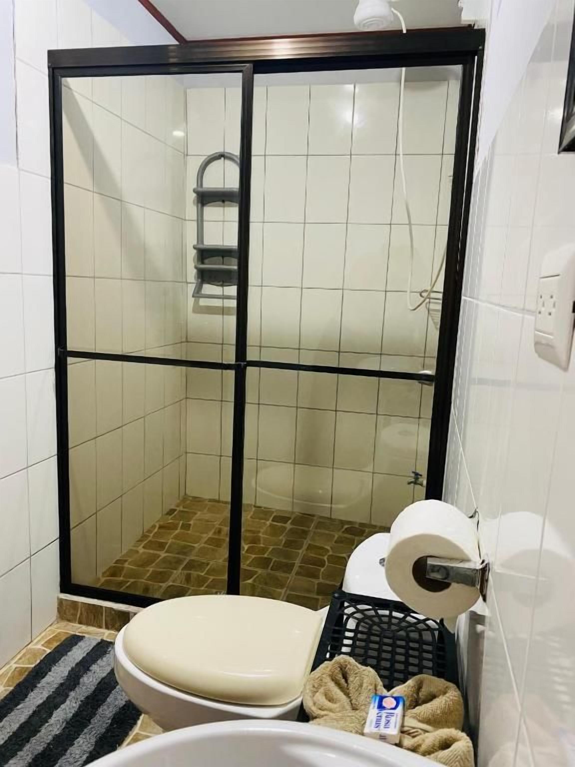 Un baño con ducha acristalada, inodoro y lavamanos.