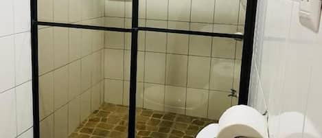 A bathroom with a glass-enclosed shower, a toilet, and a sink.