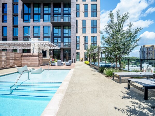 A modern building with a rooftop pool, outdoor seating, and a view of the city. - Global Luxury Suites at Reston Town Center (Reston)