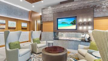Relax in style with a large flat-screen TV and scenic beach view, surrounded by comfortable seating and a stylish coffee table.