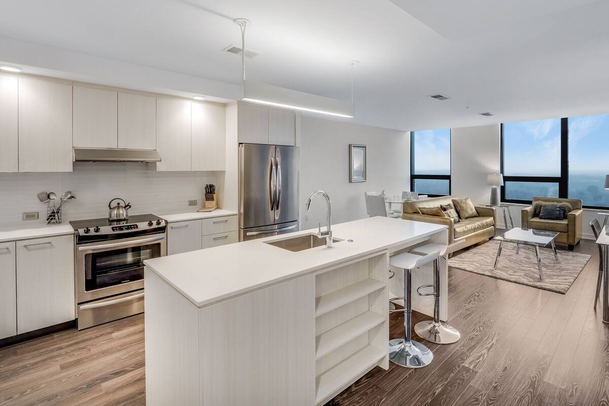 A modern kitchen with white cabinetry, stainless steel appliances, and a central island.