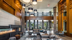 A spacious lobby with a fireplace, leather sofas, and a high ceiling with hanging lights.