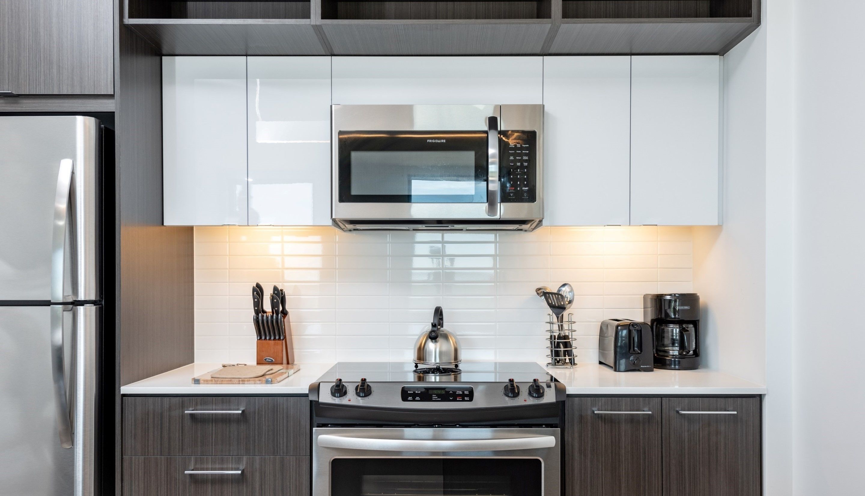 A modern kitchen with stainless steel appliances, white cabinets, and a gas stove.
