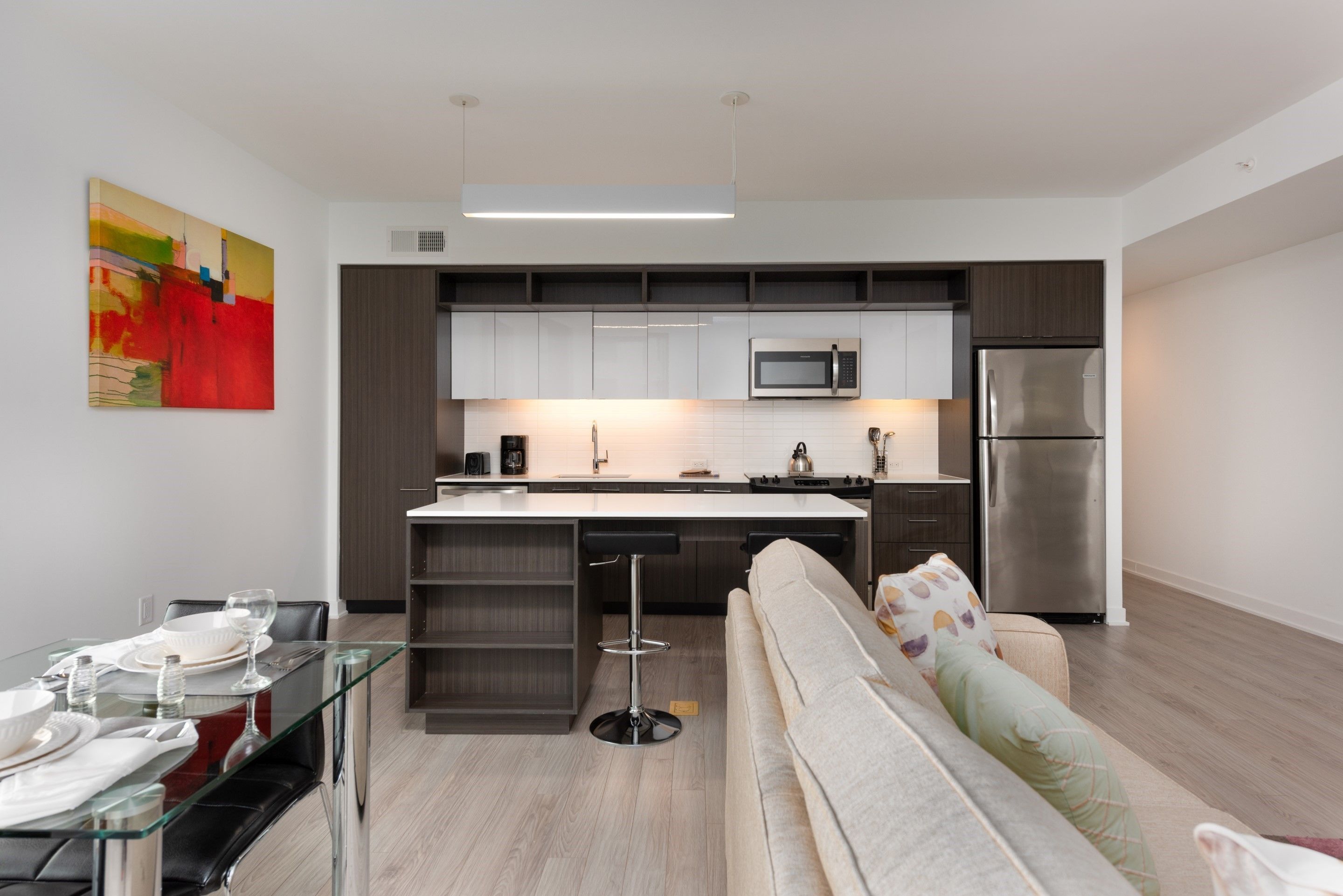 A modern kitchen with a central island, stainless steel appliances, and a dining area with a glass table and chairs.