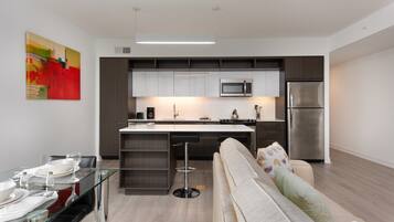 A modern kitchen with a central island, stainless steel appliances, and a dining area with a glass table and chairs.