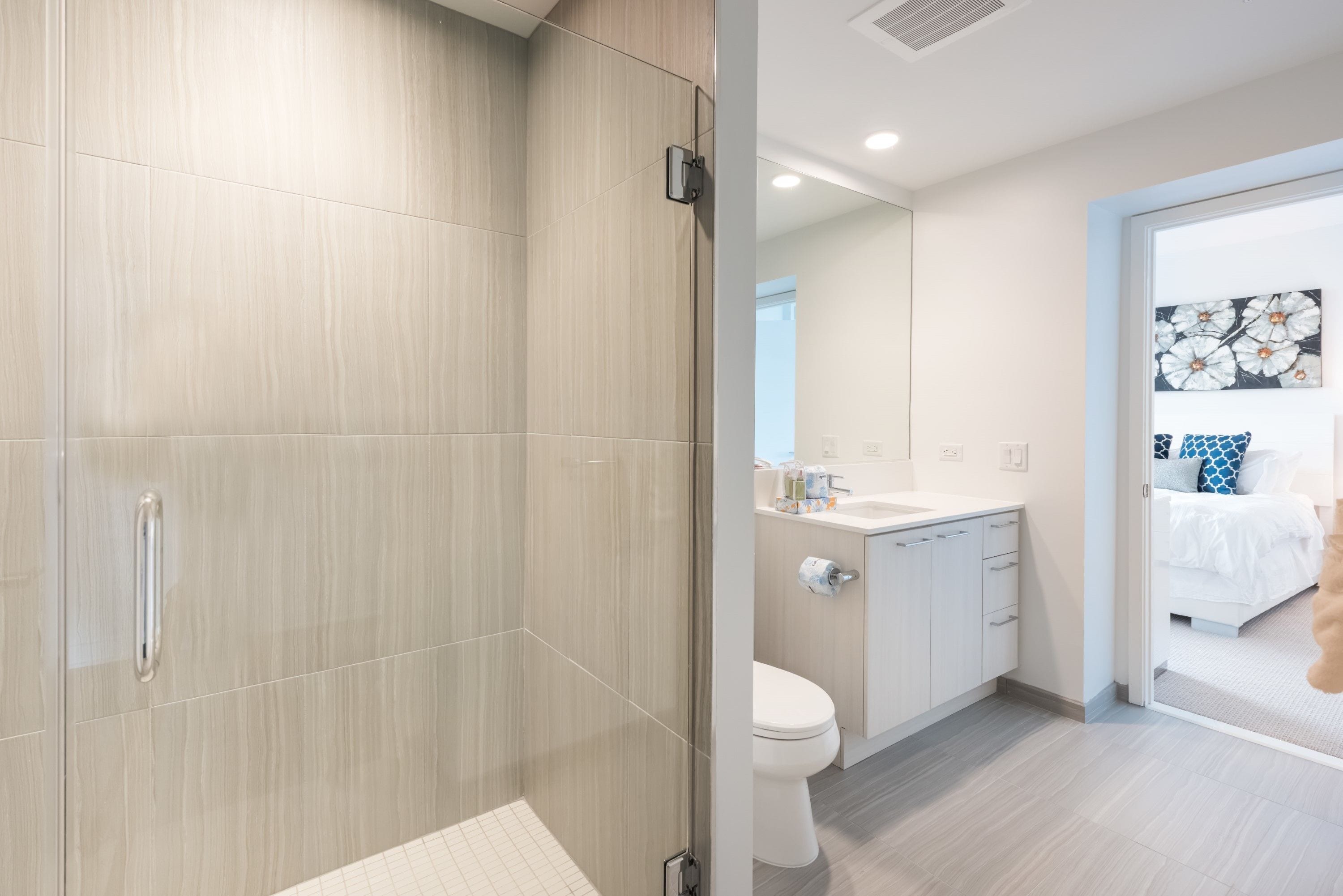 A modern bathroom with a shower, toilet, and sink.