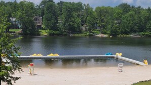 Ein Park am Seeufer mit Sandstrand, gelben und blauen Tretbooten und einer Anlegestelle.