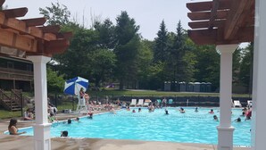 Ein Poolbereich mit mehreren Pools, Liegestühlen und einer überdachten Sitzgelegenheit.