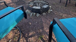 Ein Haus mit einer Terrasse, Sitzgelegenheiten im Freien und einer Feuerstelle.