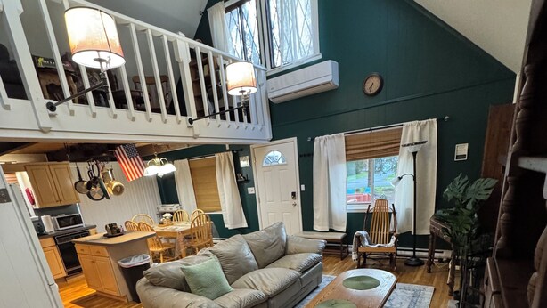 Ein Loft-Wohnraum mit hohen Decken, einem Essbereich, einer Küche und einer Treppe.