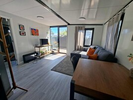 Una sala de estar moderna con un sofá, una mesa de madera y un televisor sobre un mueble.