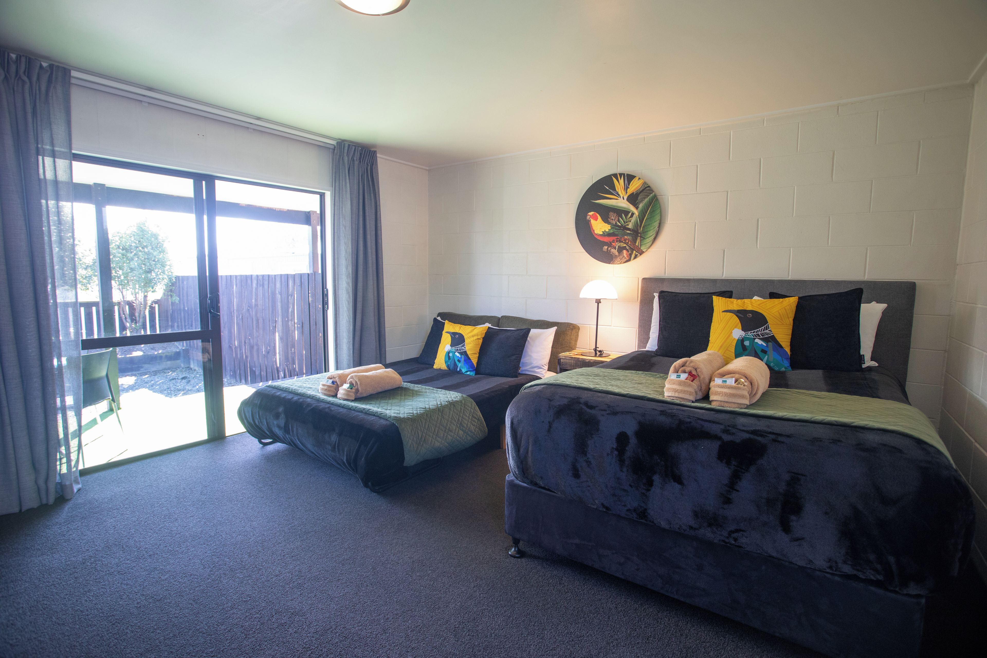 A hotel room with two beds, a large window, and a wall-mounted artwork.