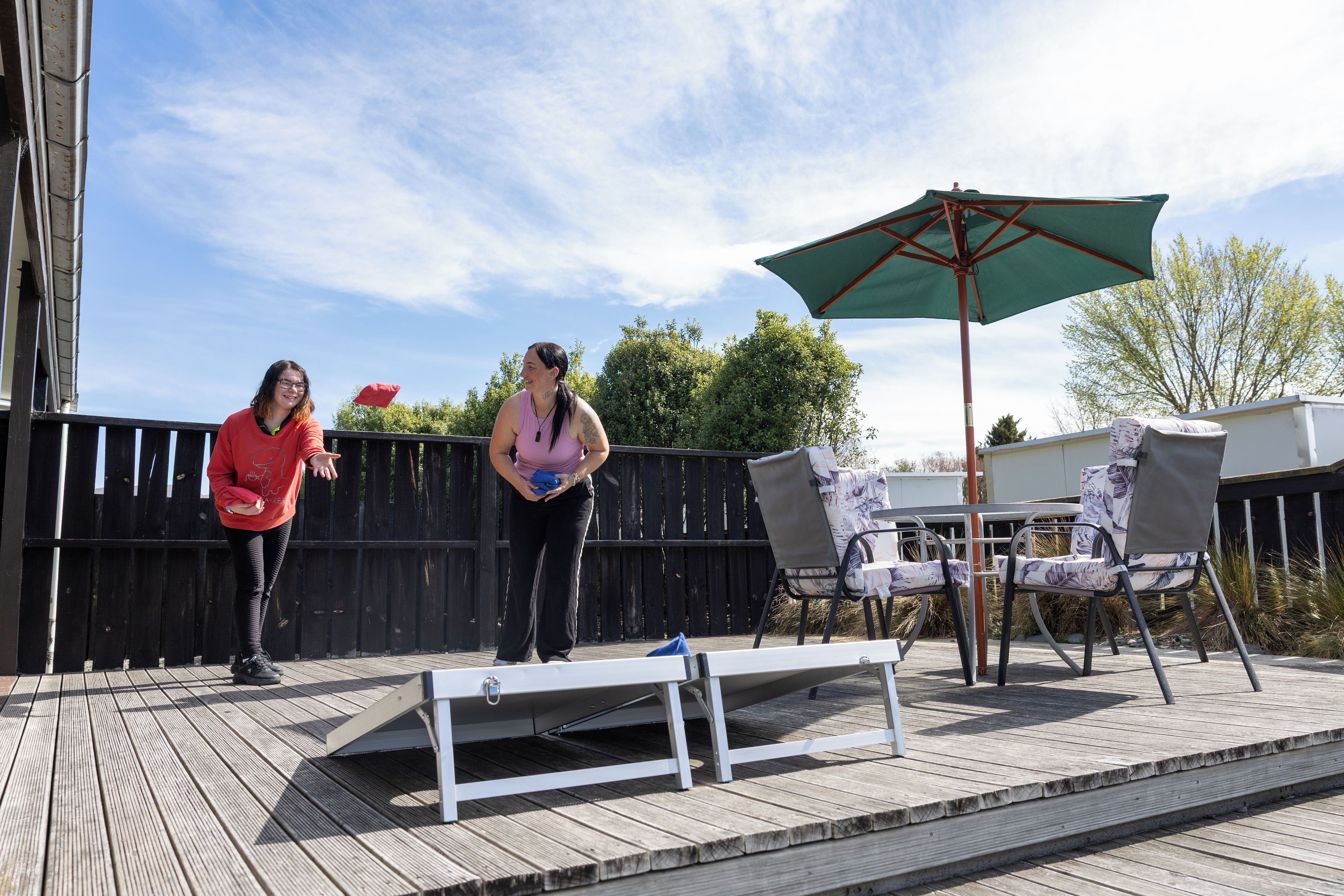 An outdoor deck with a wooden floor, a metal table, and two chairs.